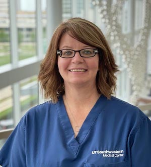 Woman with brown hair, wearing glasses and blue UTSW scrub top