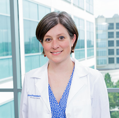 Woman with short brown hair, wearing white lab coat 