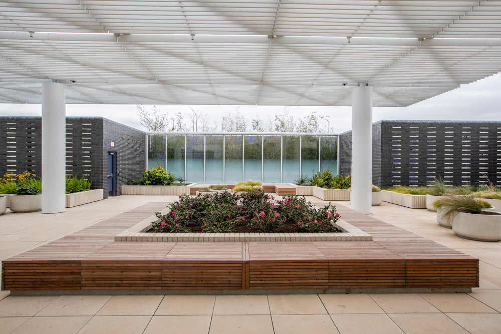 Courtyard with flowers, wood seating, and shaded cover