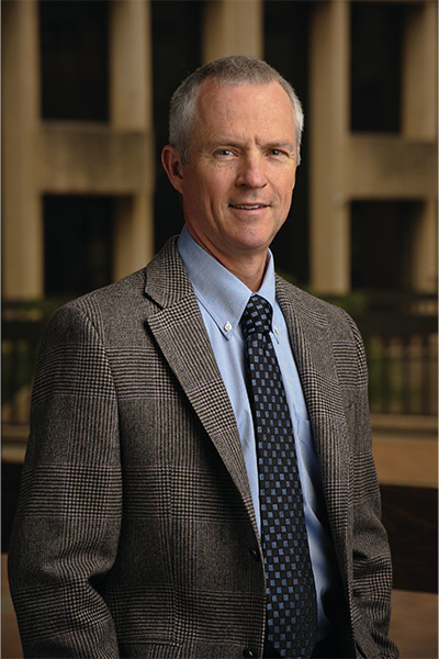 man wearing brown tweed suit against library background