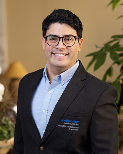 man in blue suit, blue shirt smiles 