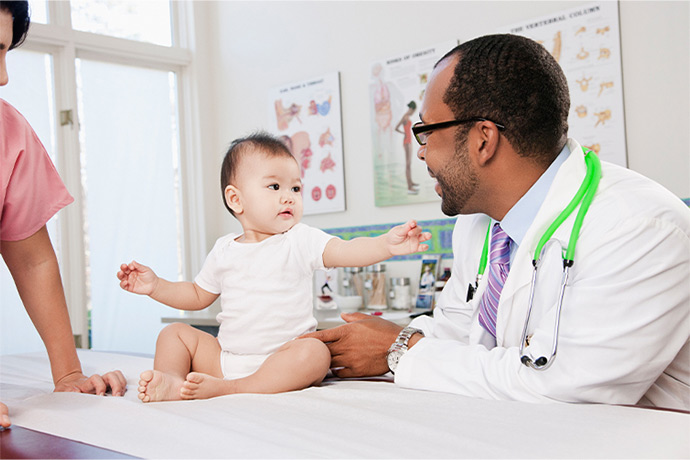 Male doctor with green stethescope interacts with baby