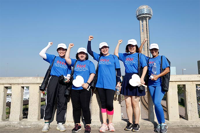 five people stading near Dallas monument with fists held high