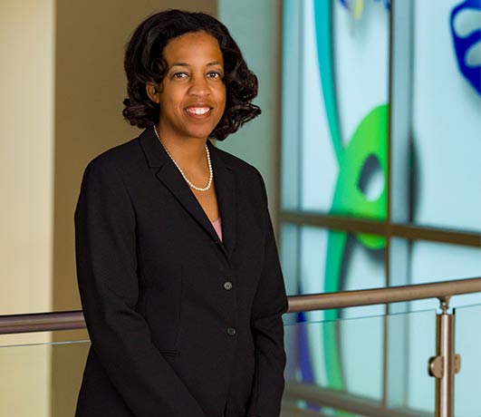 woman in black suit and pearls in front of colorful background