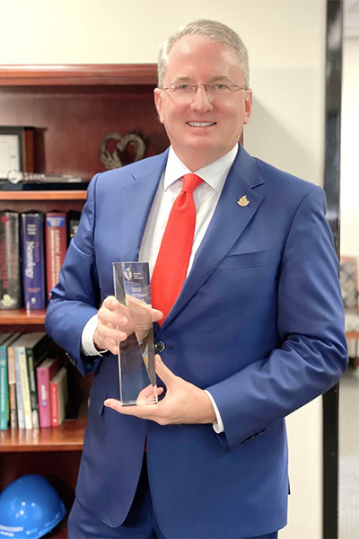 man in suite holding award in office