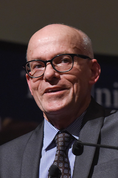 bald man in glasses wearing dark suit