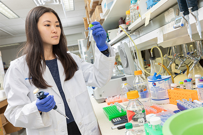 Gina Park in working in lab Woman with long dark hair in lab looking at equipment