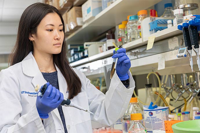 woman in white lab coats performs experiment in lab