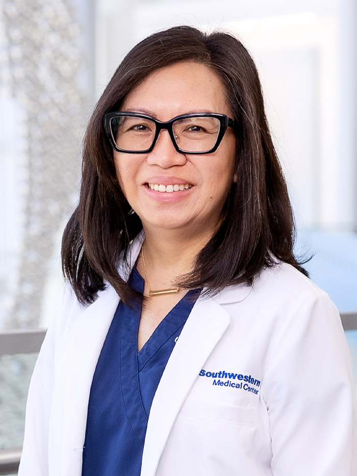 woman with shoulder length dark hair, glasses, white lab coat, blue scrubs