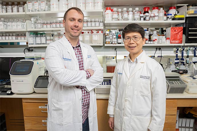 two men in white lab coats,side-by-side in lab