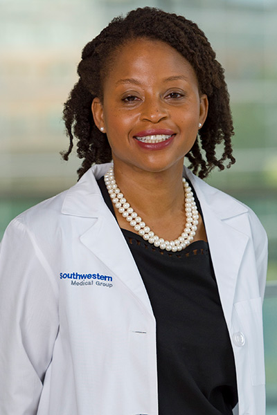 woman in black blouse and white lab coat with short brown twists hair