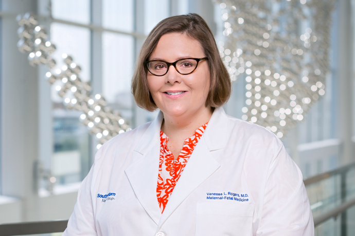 Smiling woman with short brown hair and glasses, wearing a UT Southwestern Lab coat.