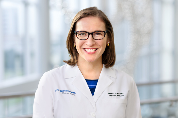 Smiling woman with curly blond hair, wearing UT Southwestern lab coat.