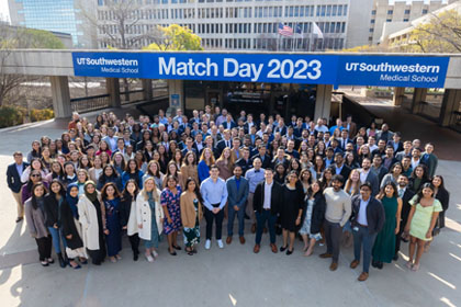 Students gathering to celebrate in front of blue Match Day 2023 banner