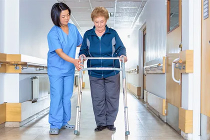 photo of medical staff assisting a woman using a walker