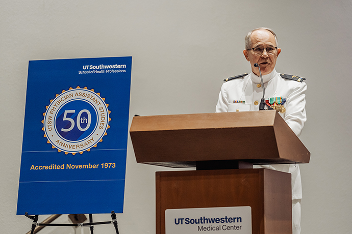 Dr. Jones, in uniform, speaking from a podium, standing next to the 50th anniversary logo.