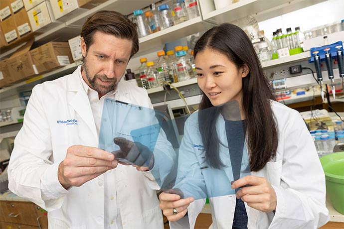 two people in white lab coats review results of an experiment in lab