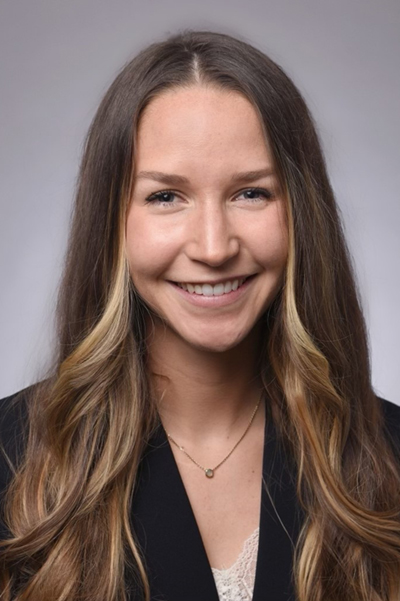 Smiling woman with long brown  hair, wearing a black jacket.