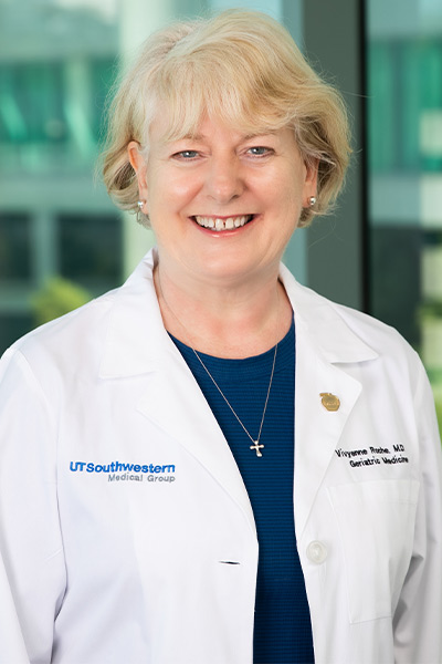 woman in black shirt, white lab coat, blonde hair