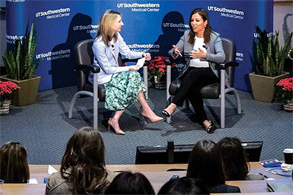 two women seated on stage in front of UTSW audience