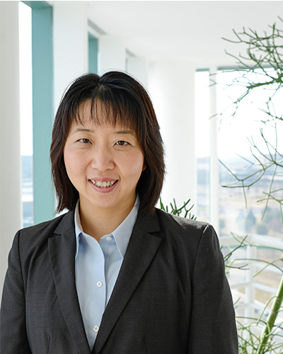 woman in dark suit, white background, green plant