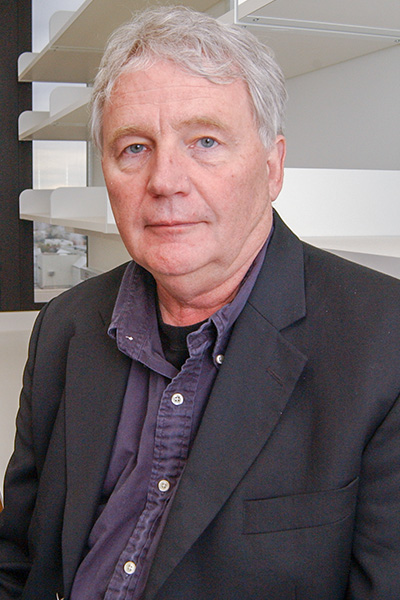 A man wearing a dark jacket, leaning against the counter in an empty lab.