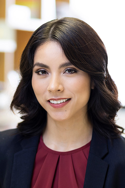 Heankel Lyons woman with long dark hair in black blazer and red shirt