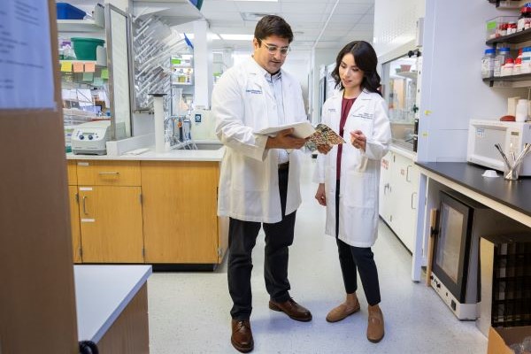 man and woman with dark hair wearing lab coats in a medical lab