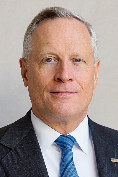 Ross Perot Jr. Man with short gray hair, wearing a dark suit, with a white shirt and blue striped tie.