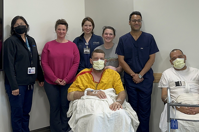 A man and 3 women posing with two male patients.