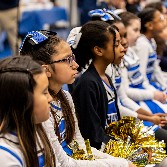little girls in cheerleading uniforms sit in a row