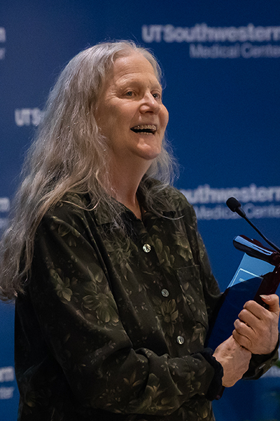 woman with long grey hair smiles and claps