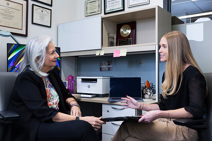 Two women seated in an office chatting.