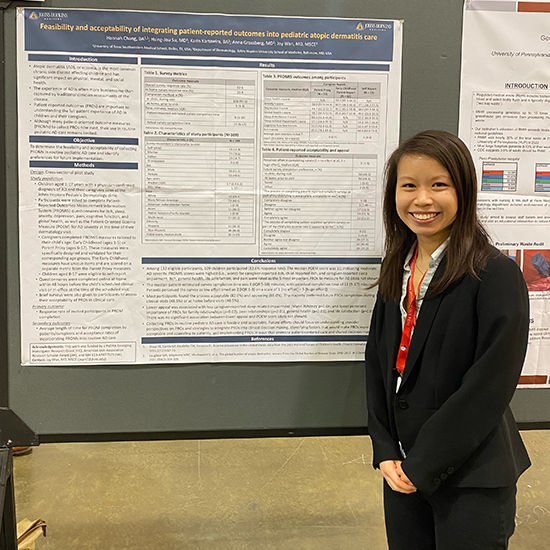 smiling woman in black suit stands in front of medical research poster display
