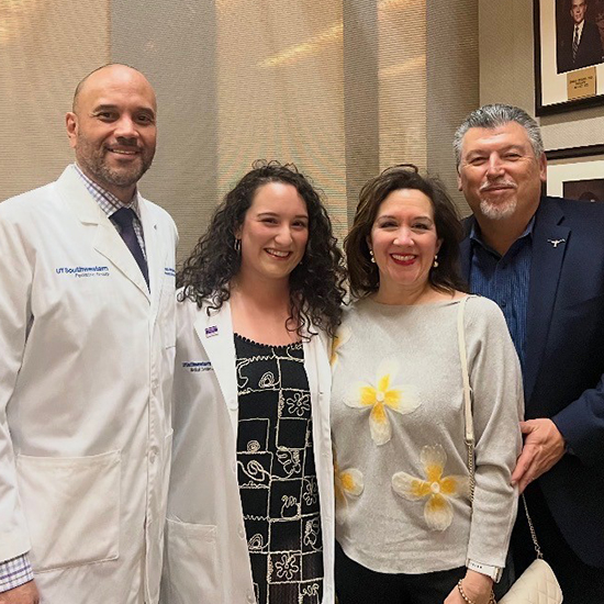 from left: tall balding man in white coat, young woman with curly dark hair in white coat, older woman in gray sweater, older man with gray hair and beard in blue shirt