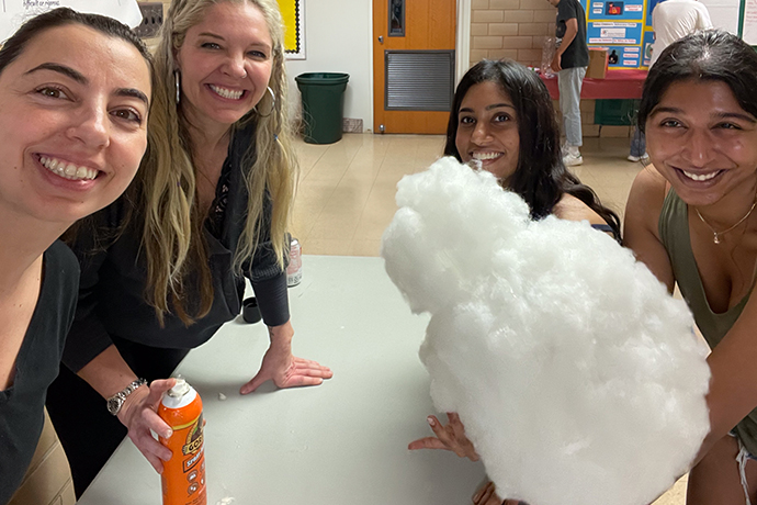 4 young women seated around a table behind bags of cotton stuffing