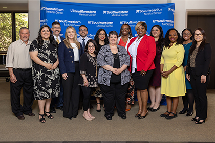 diverse group of UTSW employees stand in front of UTSW blue backdrop