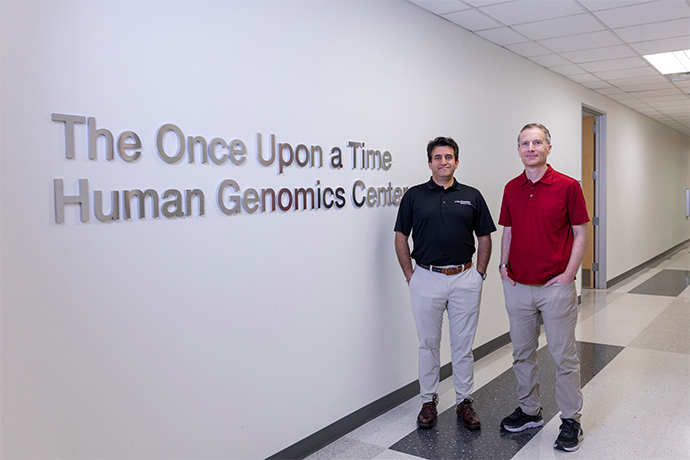 Two men walk past sign - The Once Upon a Time Human Genomics Center