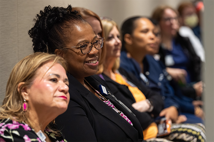 Woman in audience smiles at a remark that was made.
