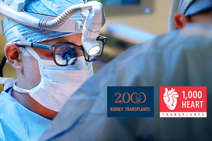 surgeon in scrubs, mask and magnifying lenses during procedure; logos to the right are 2000 kidney tranplants and 1000 heart transplants