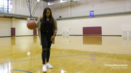 Woman on court bouncing basketball