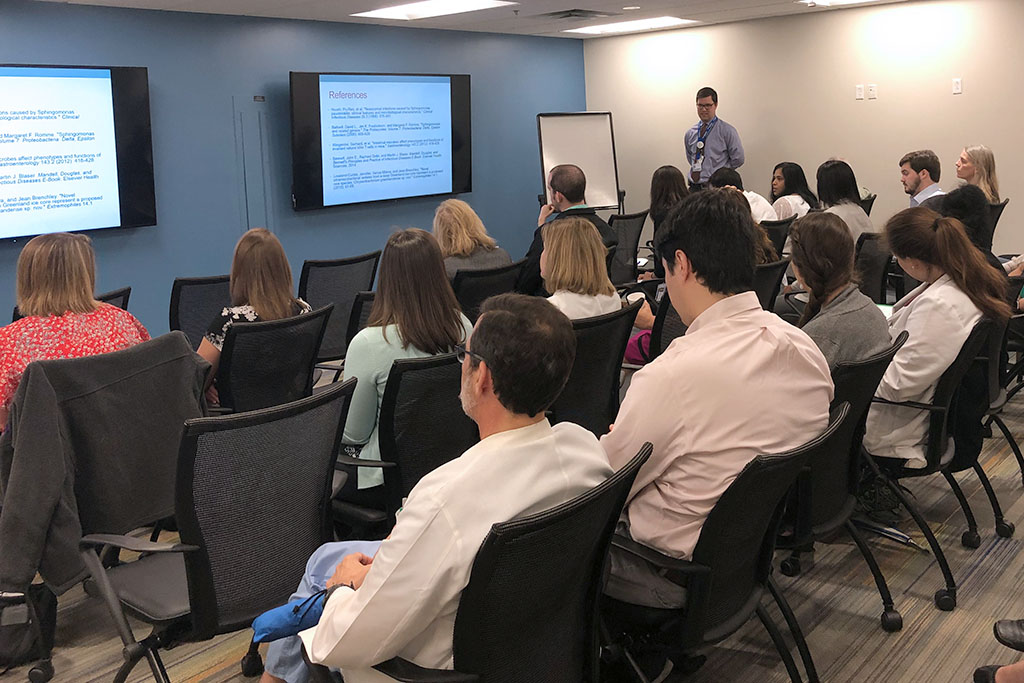 trainees in a conference room with Dr. Cutrell presenting a case