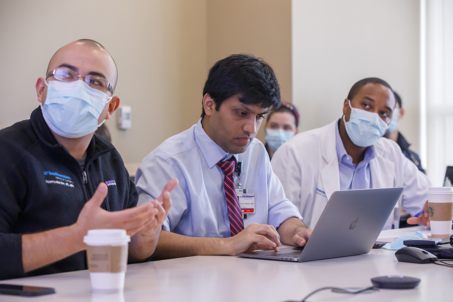 HIV Medicine Fellowship Didactics, two men with masks looking to right of frame with another man working from computer