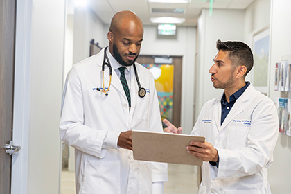 two doctors with a clipboard in a hospital hallway