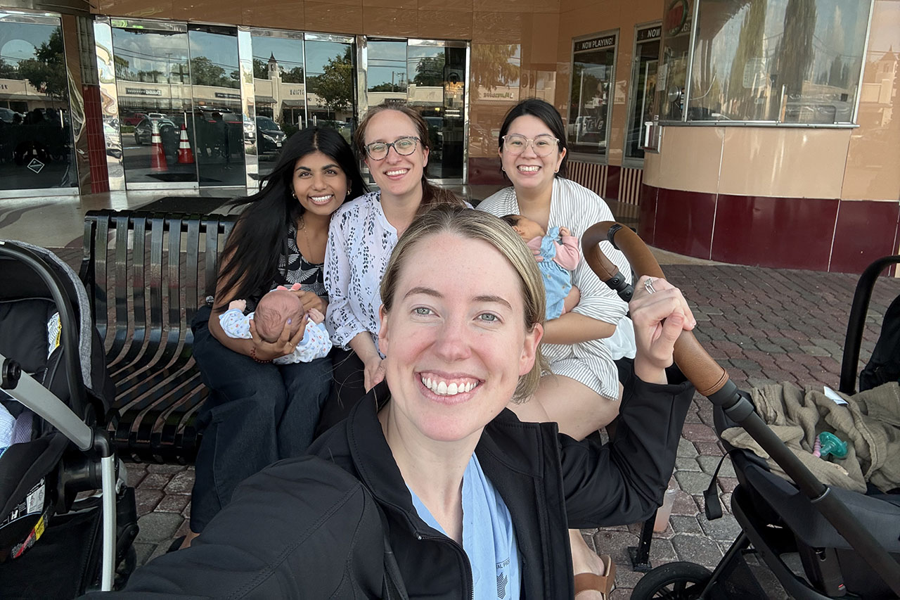 A selfie photo of four women, two of whom are holding babies