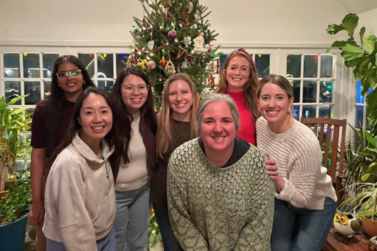 A group photo of seven women in front of a Christmas tree