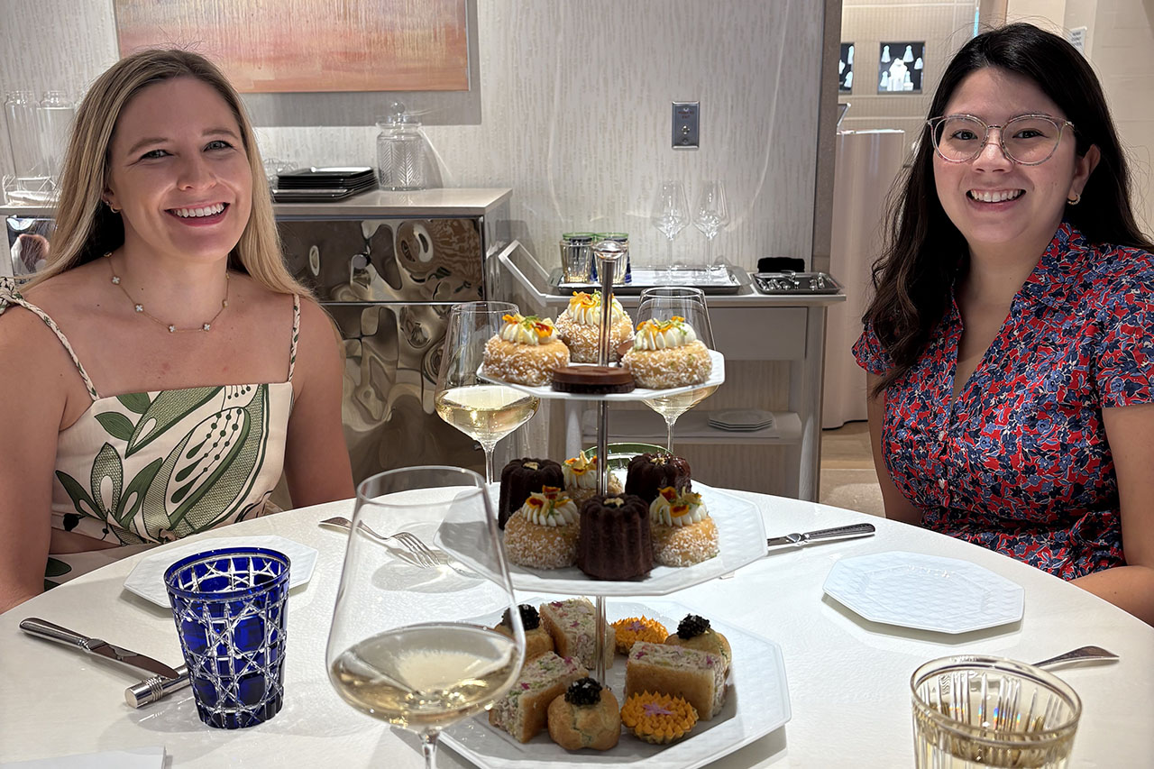 Two women sitting at a table with tea cakes