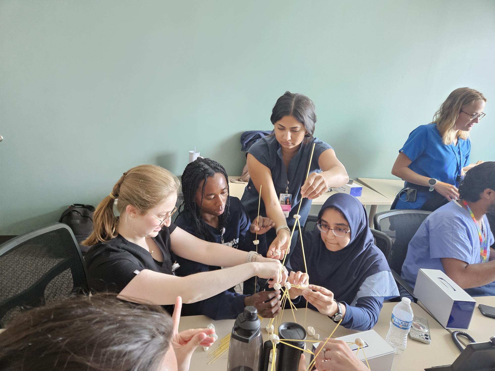 A group of residents collaborates on a hands-on team-building exercise in a classroom setting.