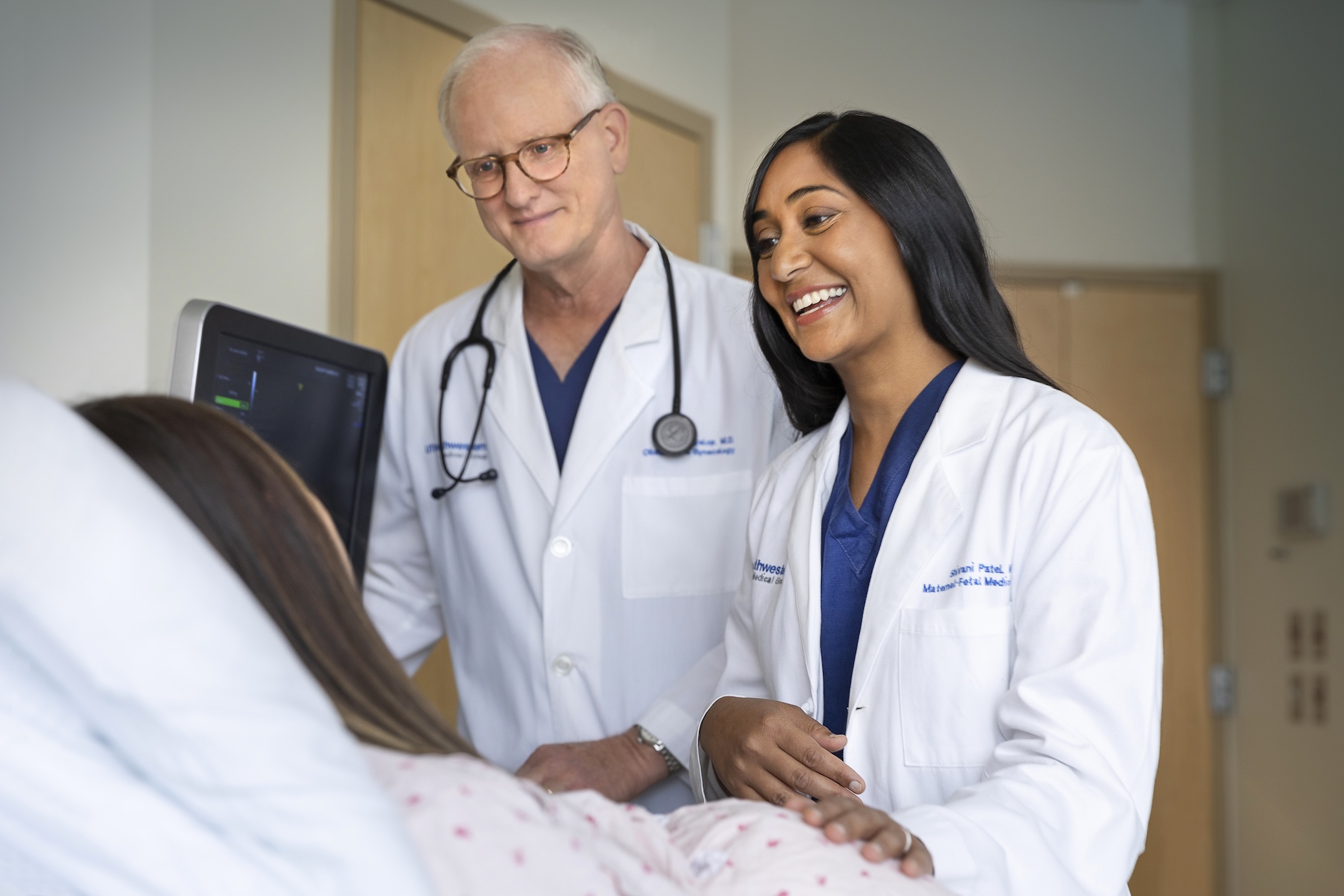 Two UT Southwestern doctors in lab coats smiling with a patient