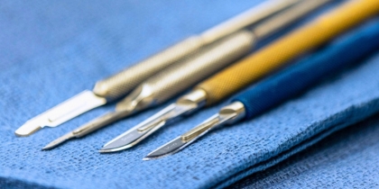 4 scalpels resting on a blue surgical drape.